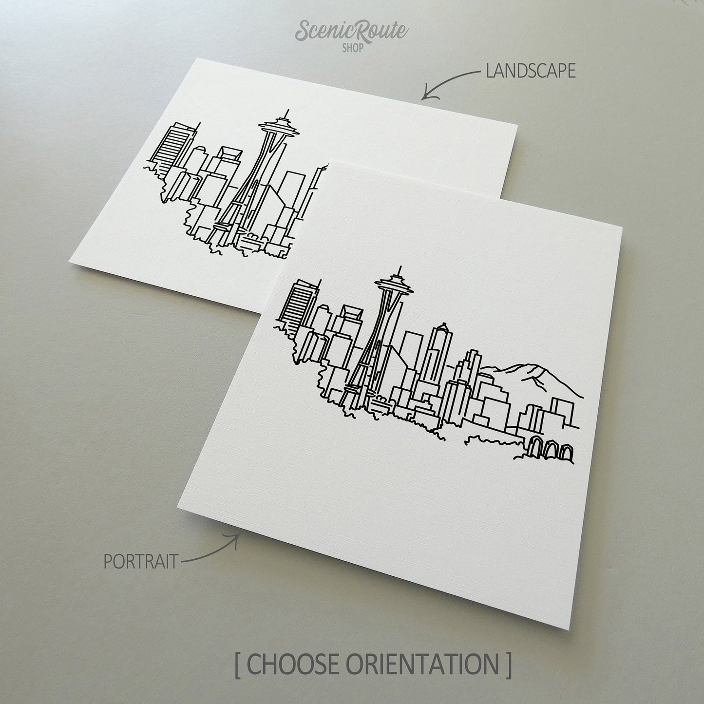 Two line art drawings of the Seattle Skyline on white linen paper with a gray background. The pieces are shown in portrait and landscape orientation for the available art print options.