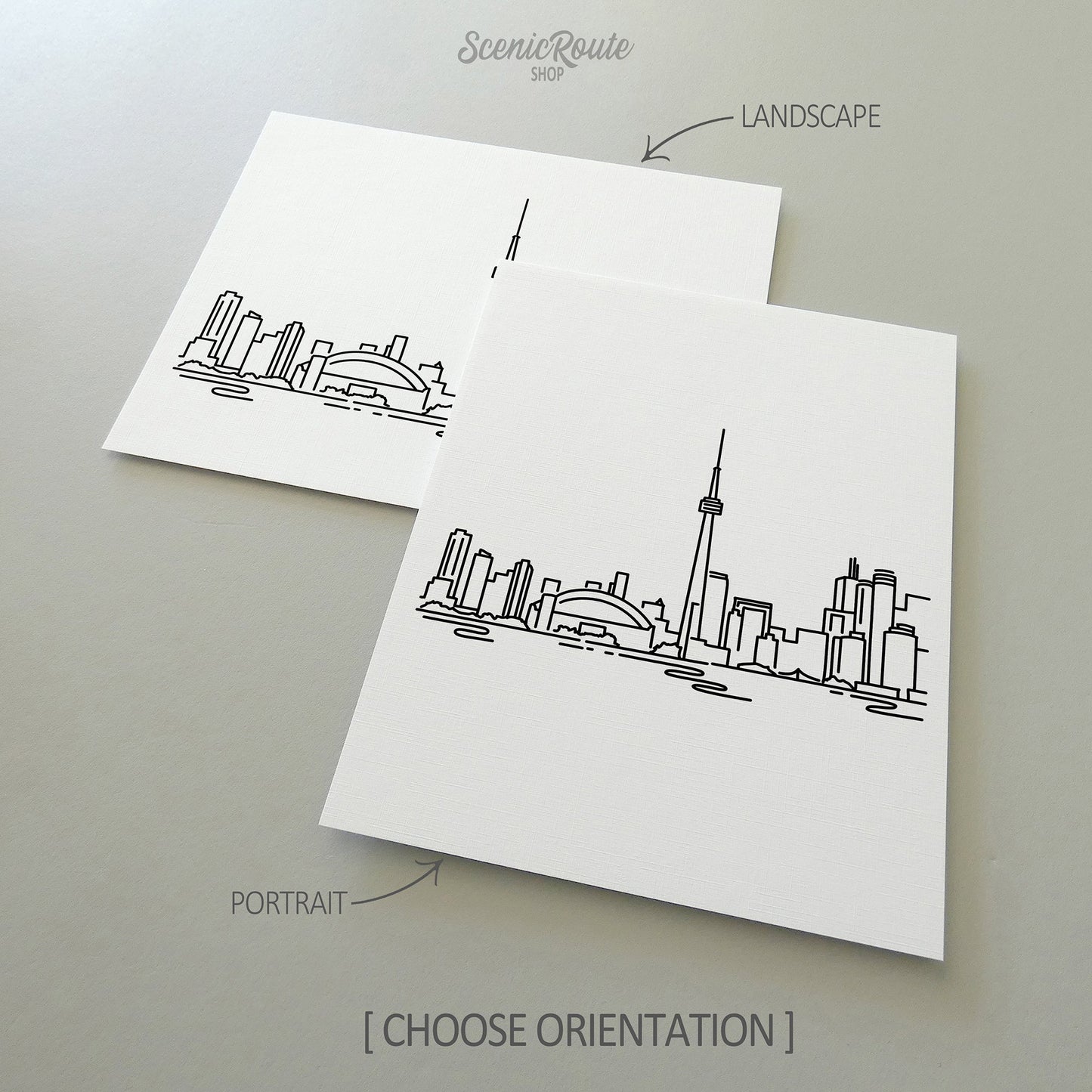Two line art drawings of the Toronto Skyline on white linen paper with a gray background. The pieces are shown in portrait and landscape orientation for the available art print options.