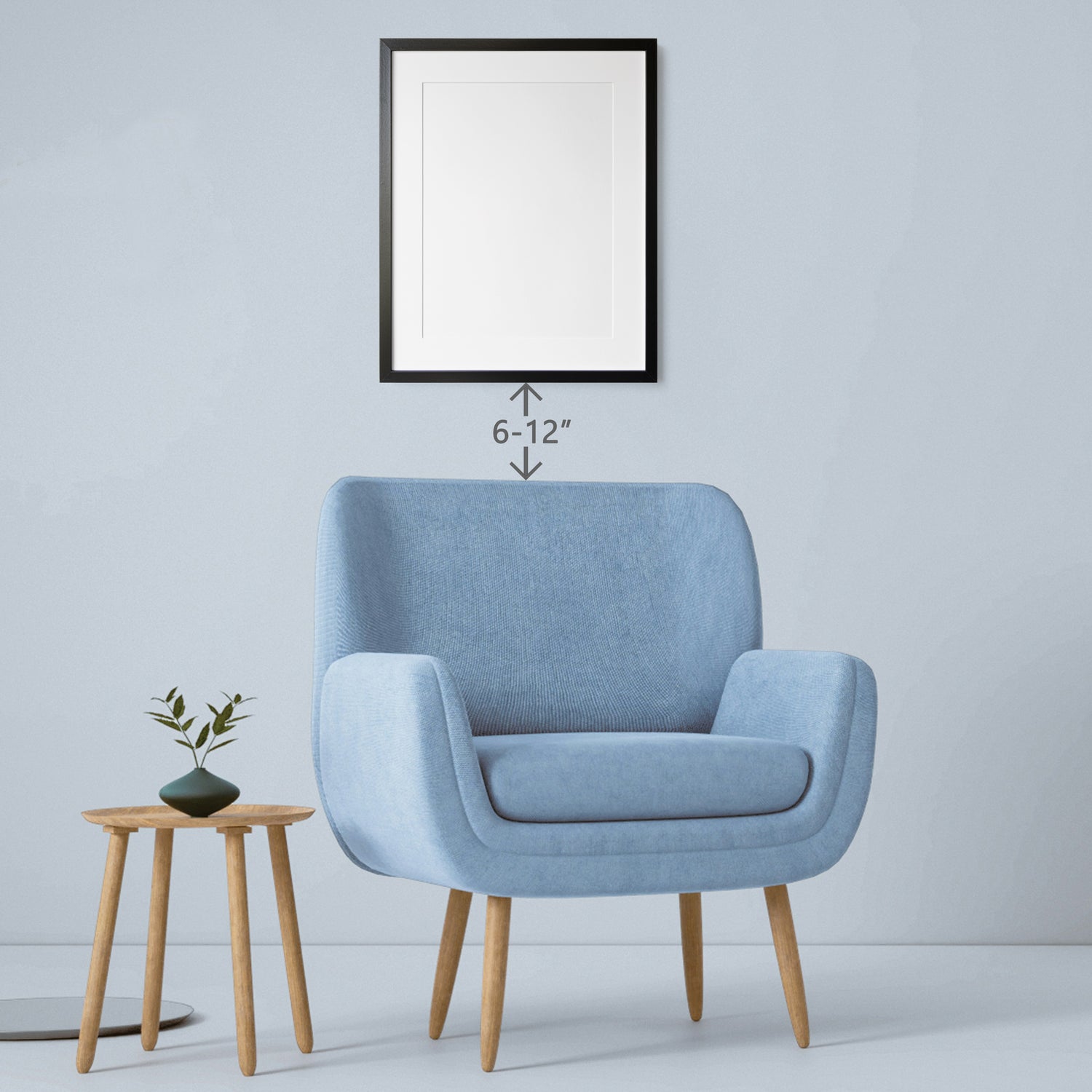 a blue chair with a small side table and picture frame hanging above it