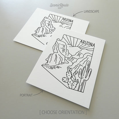 Two line art drawings of the Arizona State Outline National Park on white linen paper with a gray background.  The pieces are shown in portrait and landscape orientation for the available art print options.