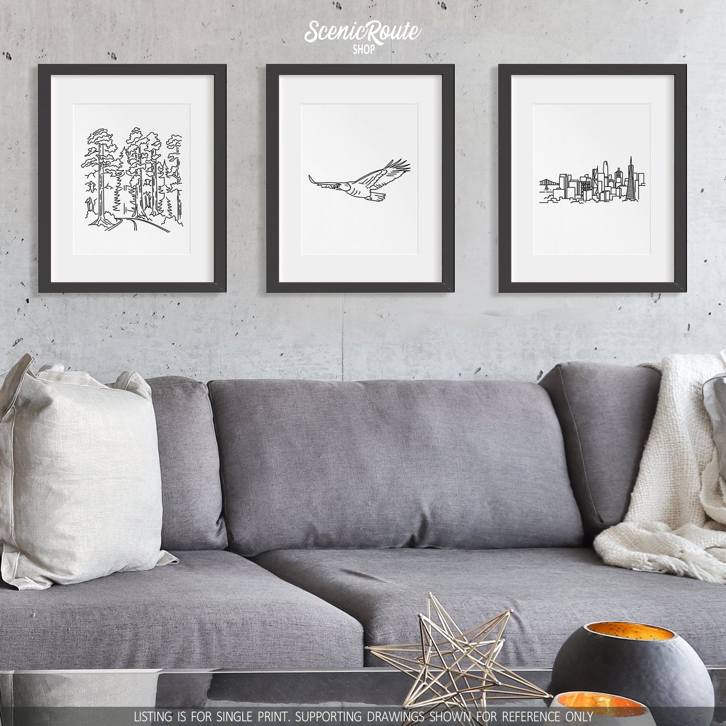 A group of three framed drawings on a wall above a couch. The line art drawings include Redwood National Park, an Eagle, and the San Francisco Skyline