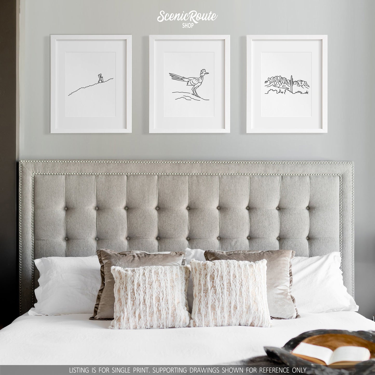 A group of three framed drawings on a white wall above a bed. The line art drawings include a person Hiking, a Roadrunner bird, and the Superstition Mountains