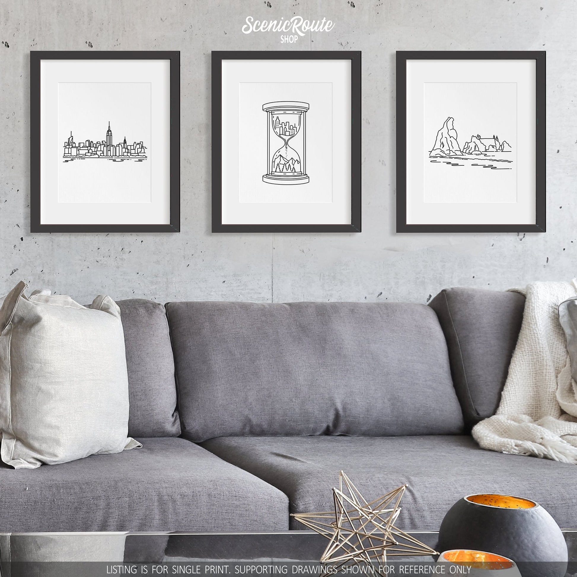 A group of three framed drawings on a wall above a couch. The line art drawings include the New York City Skyline, the Adventure Hourglass Drawing, and Haystack Rock