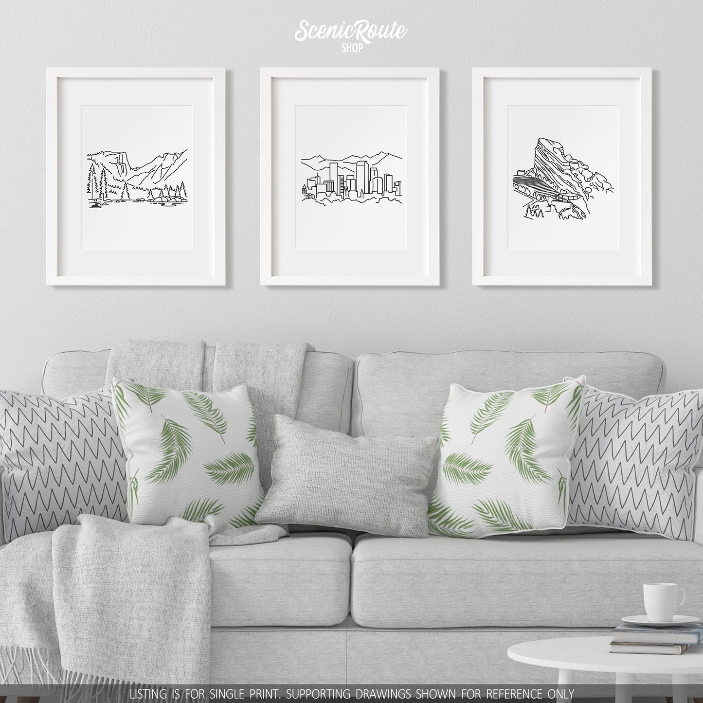 A group of three framed drawings on a wall hanging above a couch with pillows and a blanket. The line art drawings include Rocky Mountain National Park, the Denver Skyline, and Red Rocks Amphitheatre