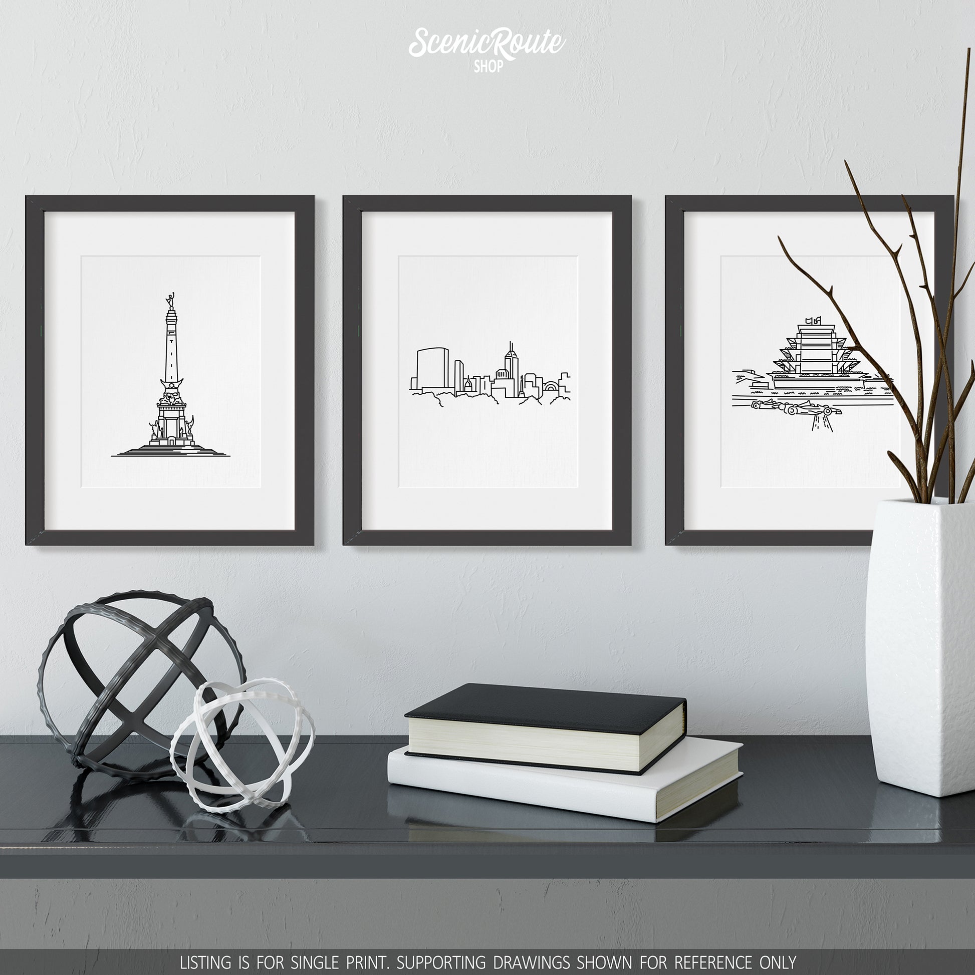 A group of three framed drawings on a wall above a dresser with books and figurines. The line art drawings include the Soldiers and Sailors Monument, Indianapolis Skyline, and Speedway Pagoda