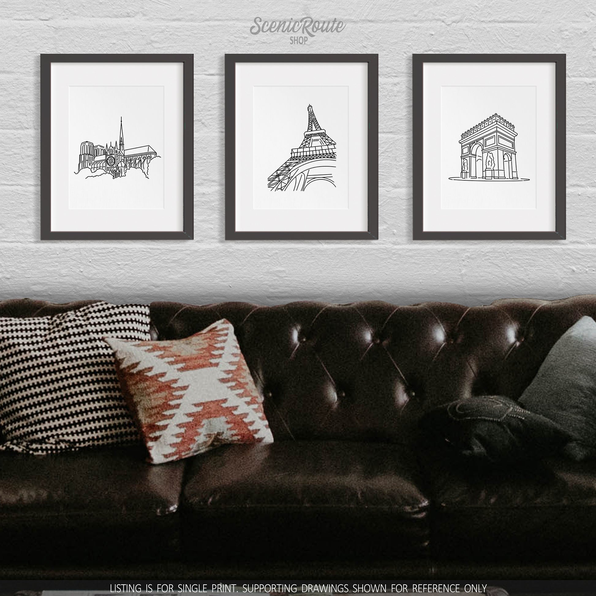 A group of three framed drawings on a wall above a couch. The line art drawings include Notre Dame Cathedral, the Eiffel Tower, and the Arc de Triomphe