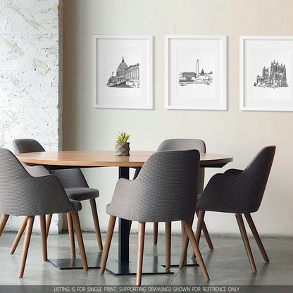 A group of three framed drawings on a white wall hanging above a table and chairs. The line art drawings include the Capitol, the Washington DC Skyline, and the National Cathedral