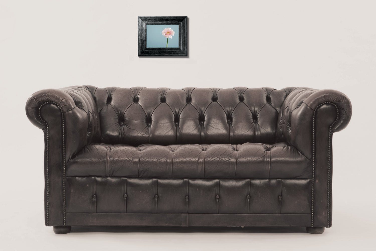 A leather sofa with a tiny framed picture hanging above it