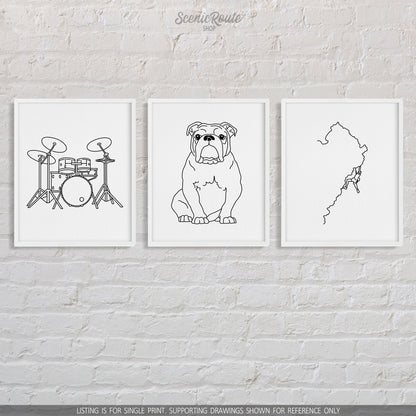 A group of three framed drawings on a brick wall.  The line art drawings include a set of Drums, a Bulldog, and a person Rock Climbing