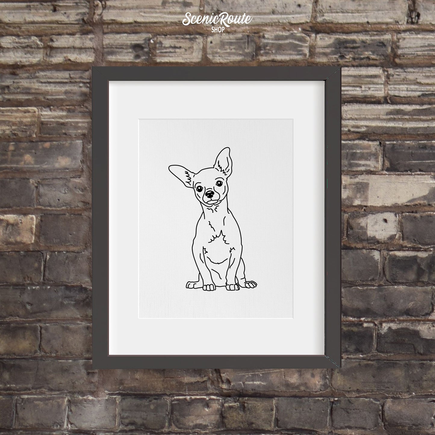 A framed line art drawing of a Chihuahua dog on a dark brick wall