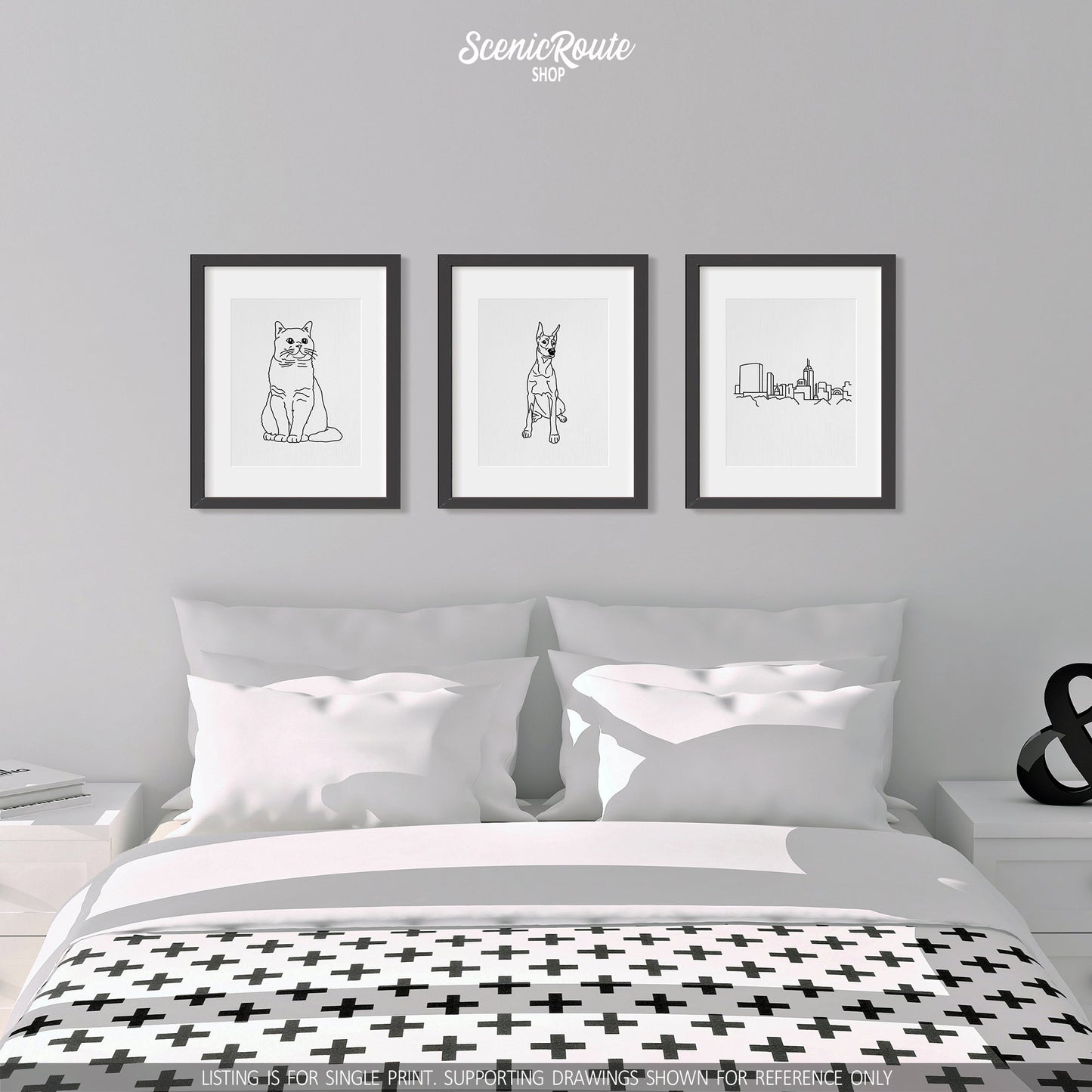 A group of three framed drawings on a white wall above a bed on a white wall. The line art drawings include a British Shorthair cat, a Doberman dog, and the Indianapolis Skyline