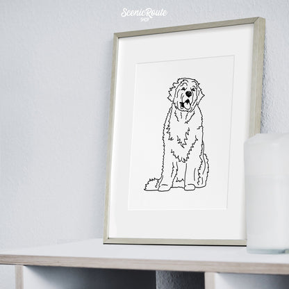 A framed line art drawing of a Newfoundland dog on a bookshelf