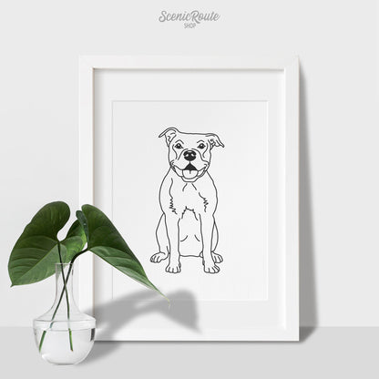 A framed line art drawing of a Pitbull dog on a table with a plant