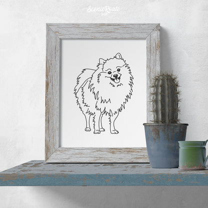 A framed line art drawing of a Pomeranian dog on a blue shelf with a cactus