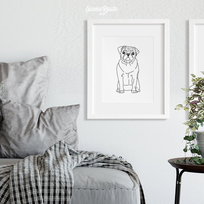 A framed line art drawing of a Pug dog above a couch with a blanket