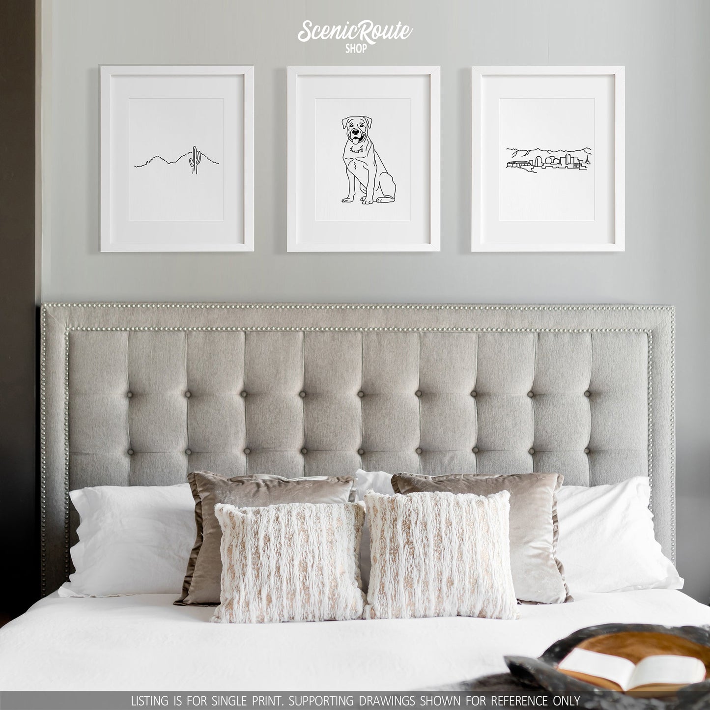 A group of three framed drawings on a gray wall above a bed. The line art drawings include Camelback Mountain, a Rottweiler dog, and the Phoenix Skyline