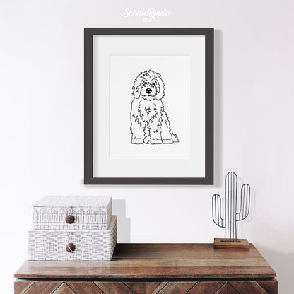 A framed line art drawing of a Sheepadoodle dog above a table