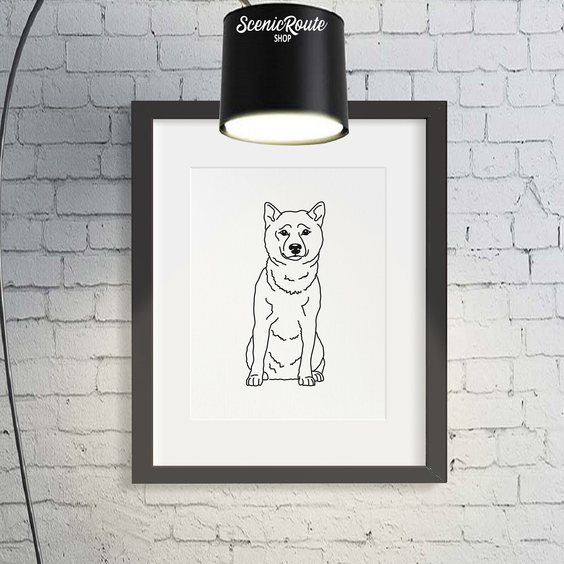 A framed line art drawing of a Shiba Inu dog on a brick wall with a lamp