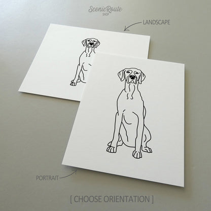 Two line art drawings of a Weimaraner dog on white linen paper with a gray background.  The pieces are shown in portrait and landscape orientation for the available art print options.
