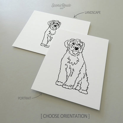 Two line art drawings of a Wheaten Terrier dog on white linen paper with a gray background.  The pieces are shown in portrait and landscape orientation for the available art print options.
