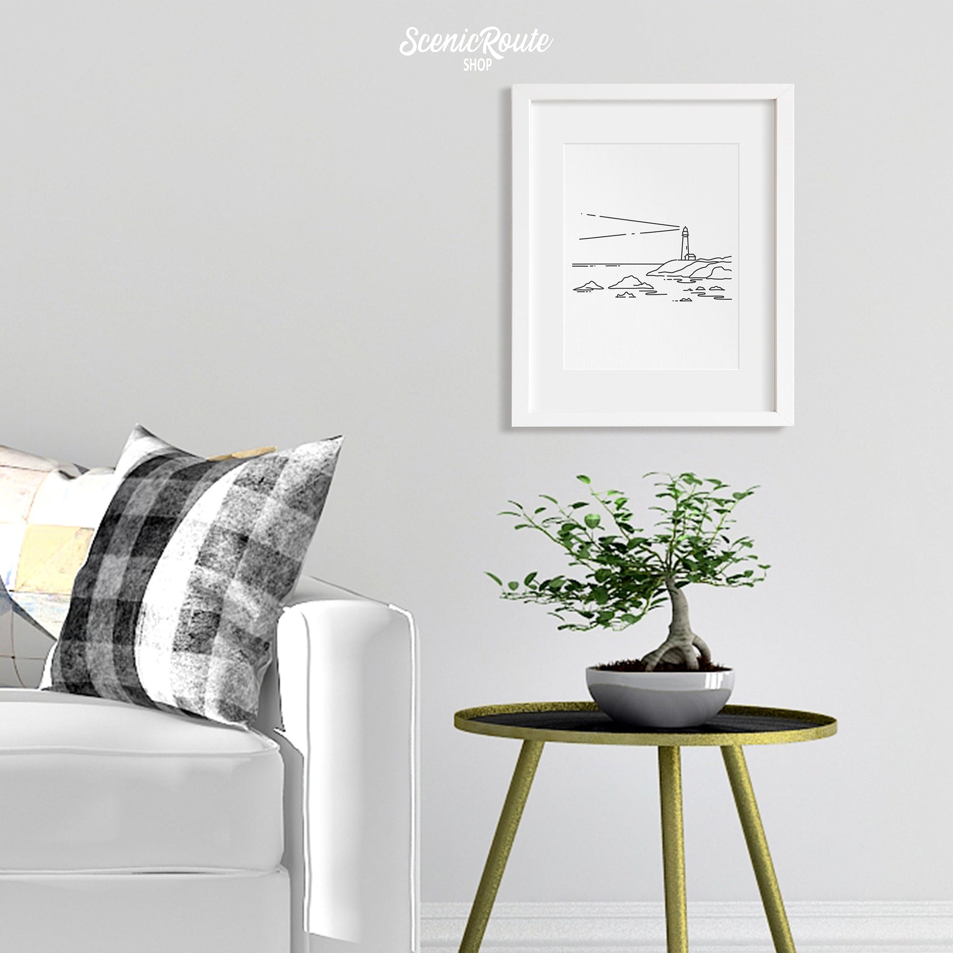 A framed line art drawing of A Lighthouse above a round table with a plant