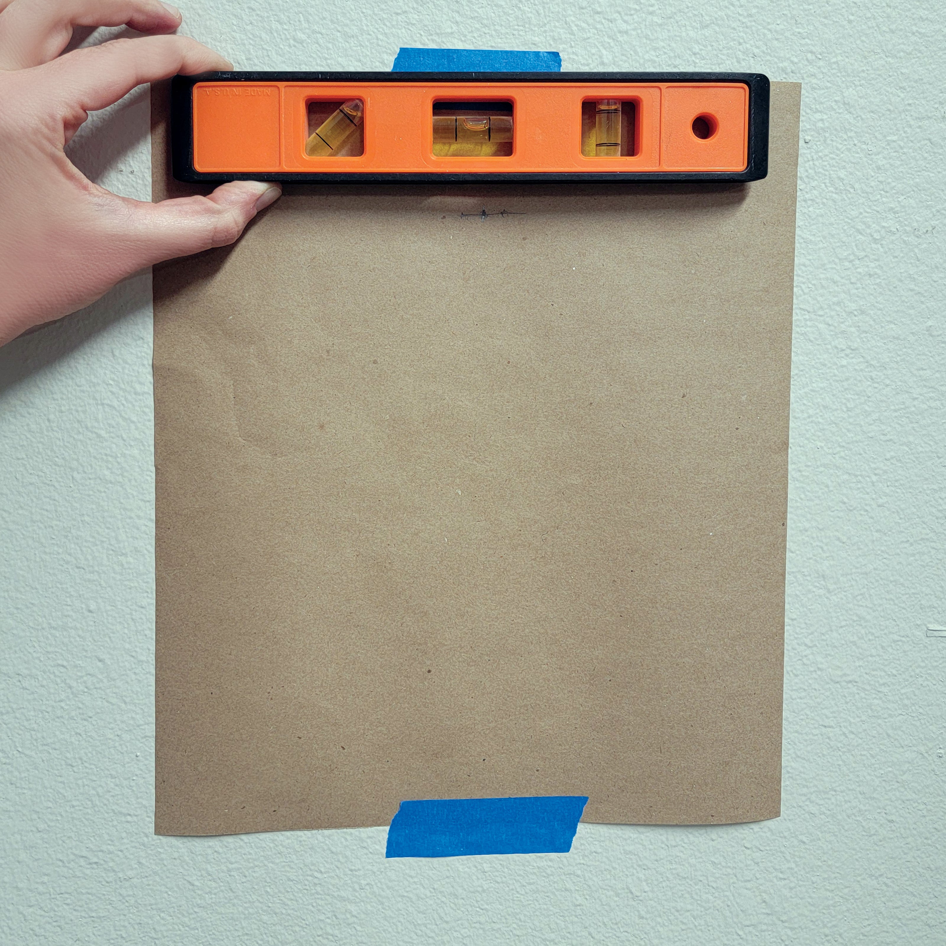 a piece of kraft paper taped to a wall with a level at the top edge