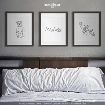 A group of three framed drawings on a white wall above a bed. The line art drawings include a Schnauzer dog, Camping, and the Statue of Liberty