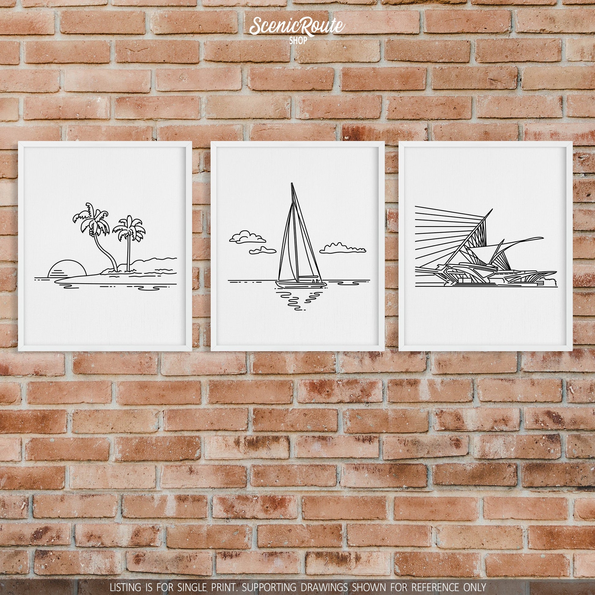 A group of three framed drawings on a brick wall. The line art drawings include an Island, Sailing, and the Milwaukee Art Museum