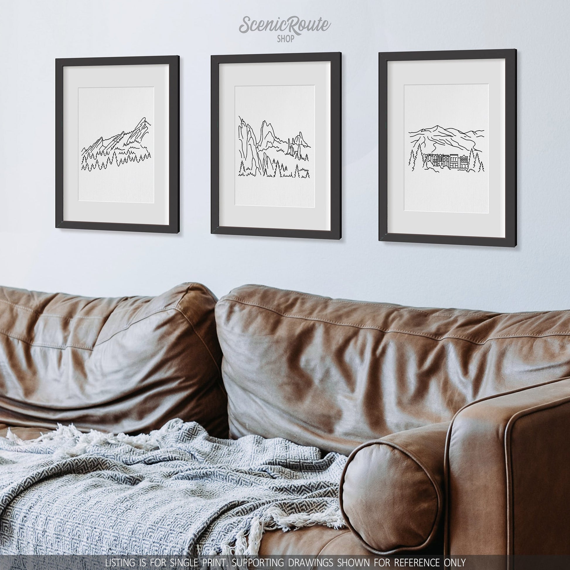 A group of three framed drawings on a wall above a couch. The line art drawings include the Flatirons, the Garden of the Gods, and Breckenridge
