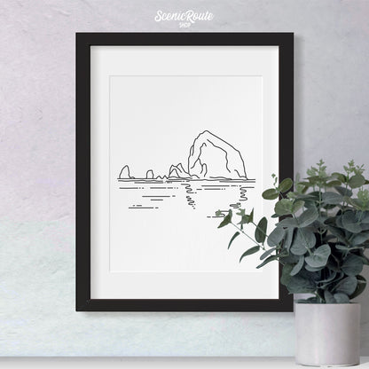 A framed line art drawing of Haystack Rock with a plant