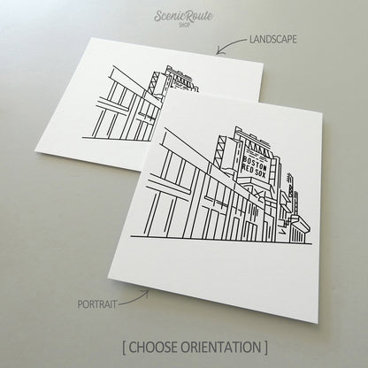 Two line art drawings of Fenway Park on white linen paper with a gray background.  The pieces are shown in portrait and landscape orientation for the available art print options.