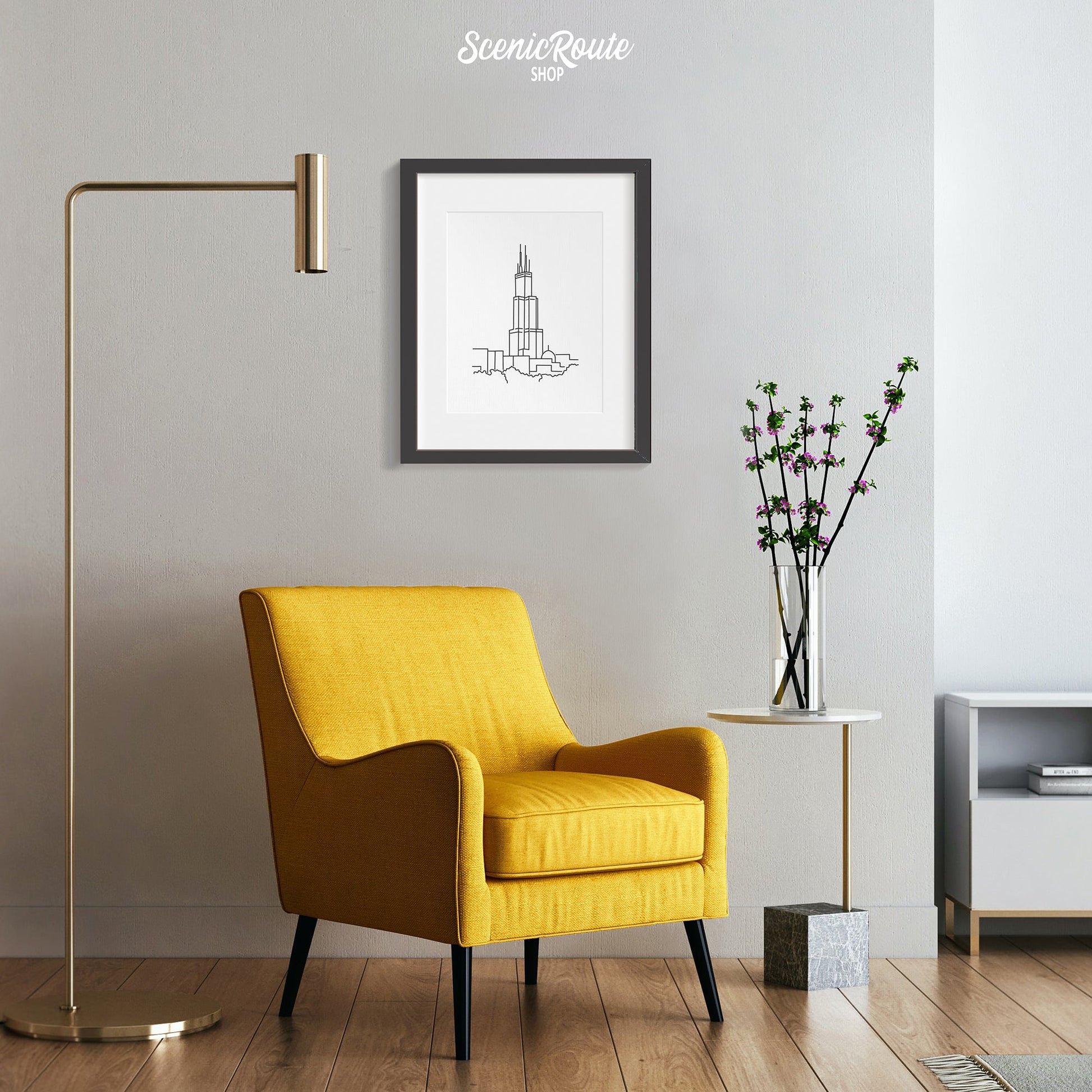 A framed line art drawing of the Willis Sears Tower hanging above a yellow chair