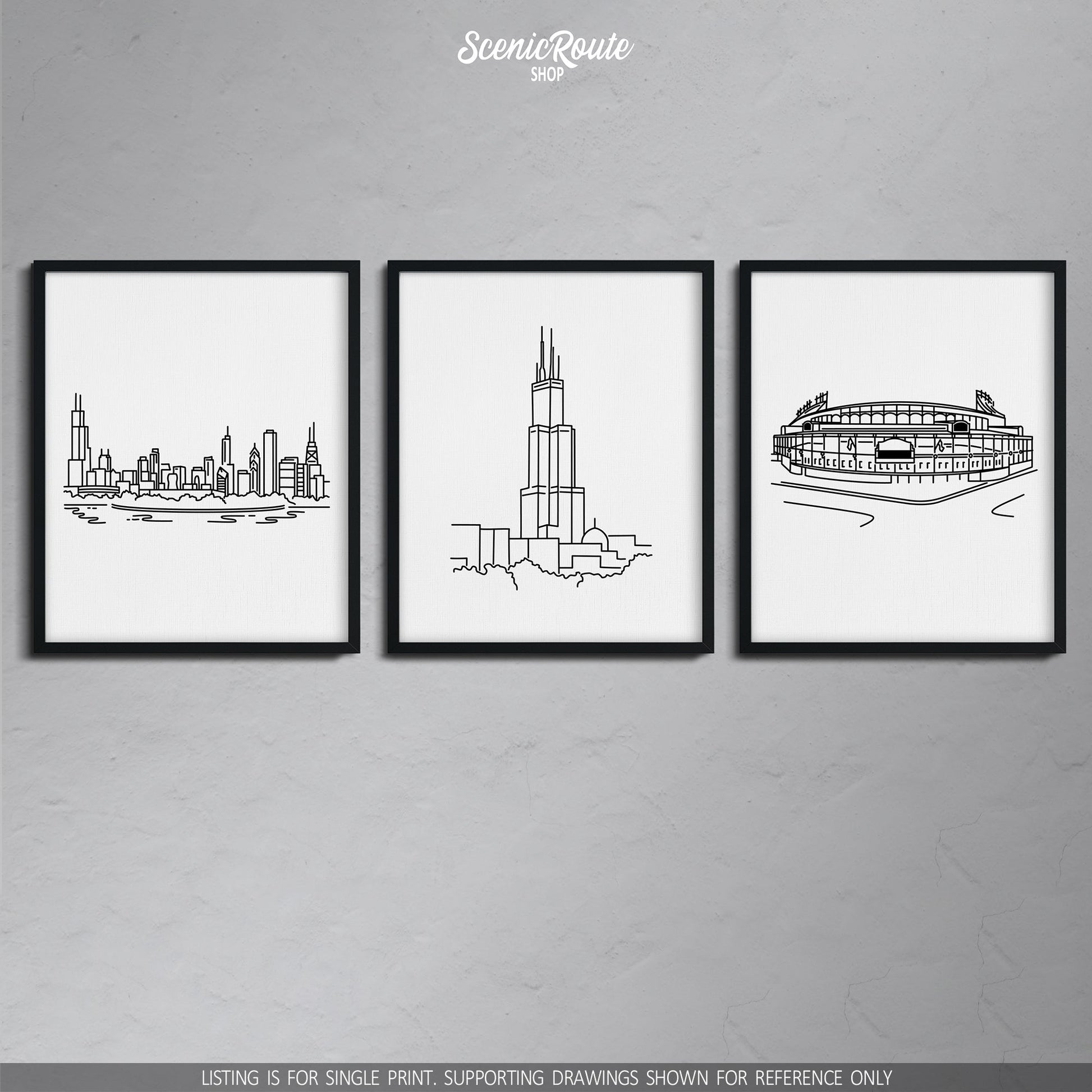 A group of three framed drawings on a gray wall. The line art drawings include the Chicago Skyline, Willis Sears Tower, and Wrigley Field