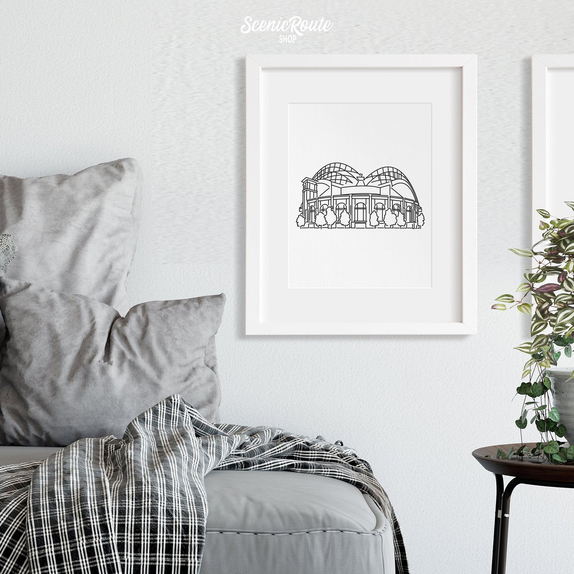 A framed line art drawing of the Brewers Ballpark above a couch and blanket