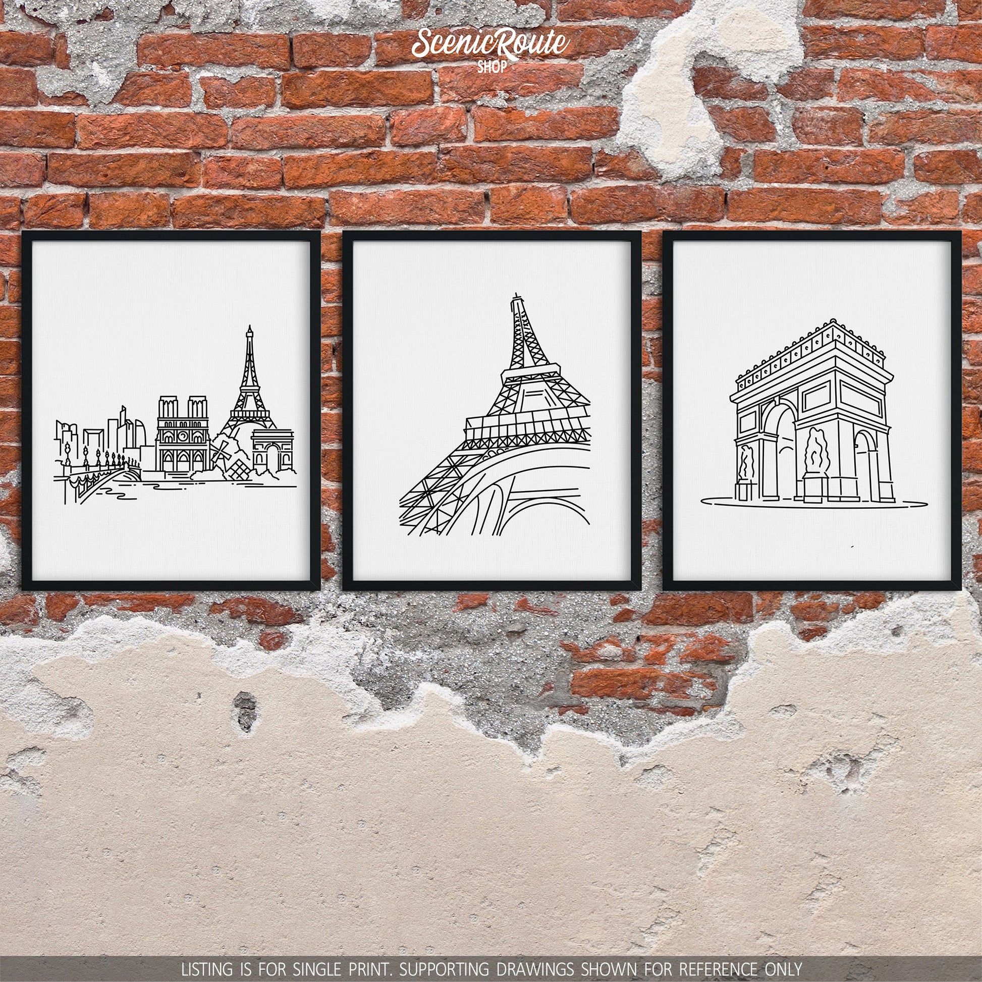 A group of three framed drawings on a brick wall. The line art drawings include the Paris Skyline, Eiffel Tower, and Arc de Triomphe
