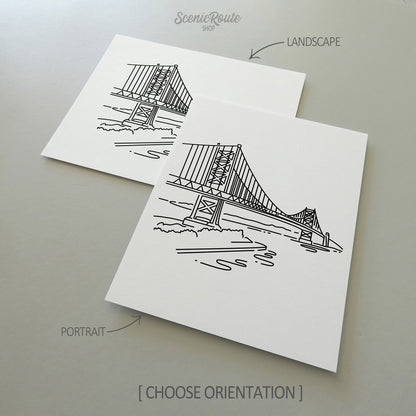 Two line art drawings of the Ben Franklin Bridge on white linen paper with a gray background.  The pieces are shown in portrait and landscape orientation for the available art print options.