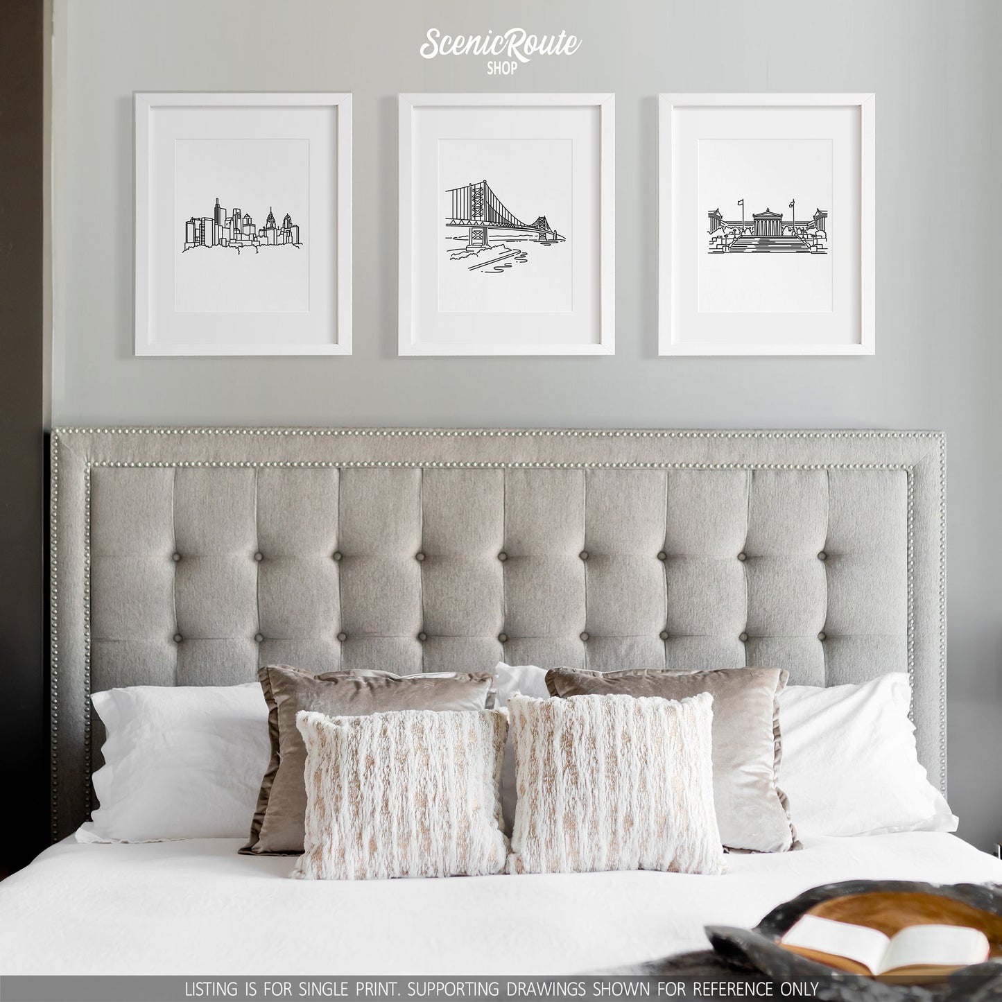 A group of three framed drawings on a white wall above a bed. The line art drawings include the Philadelphia Skyline, Ben Franklin Bridge, and Philadelphia Art Museum