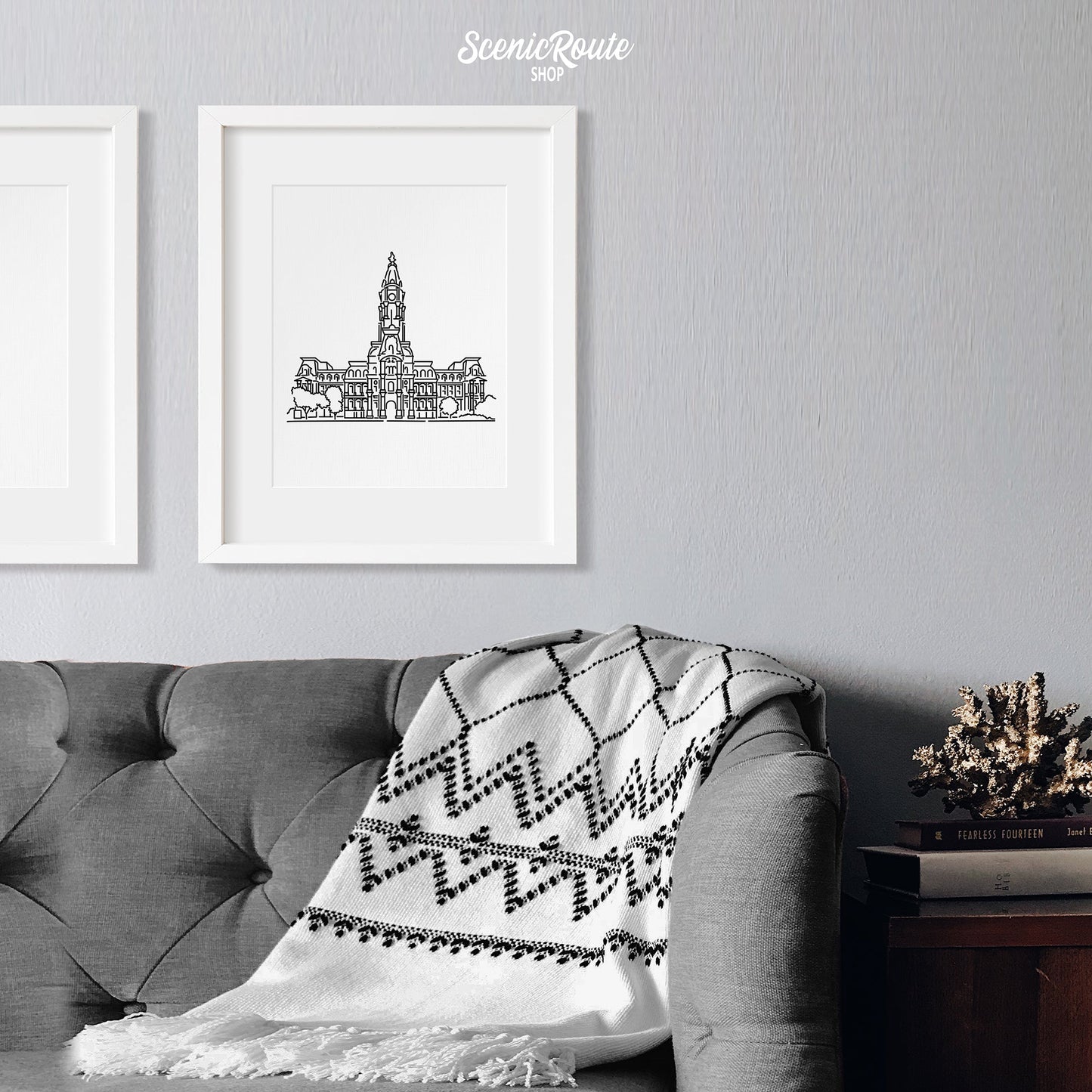 A framed line art drawing of Philadelphia City Hall above a sofa with a blanket