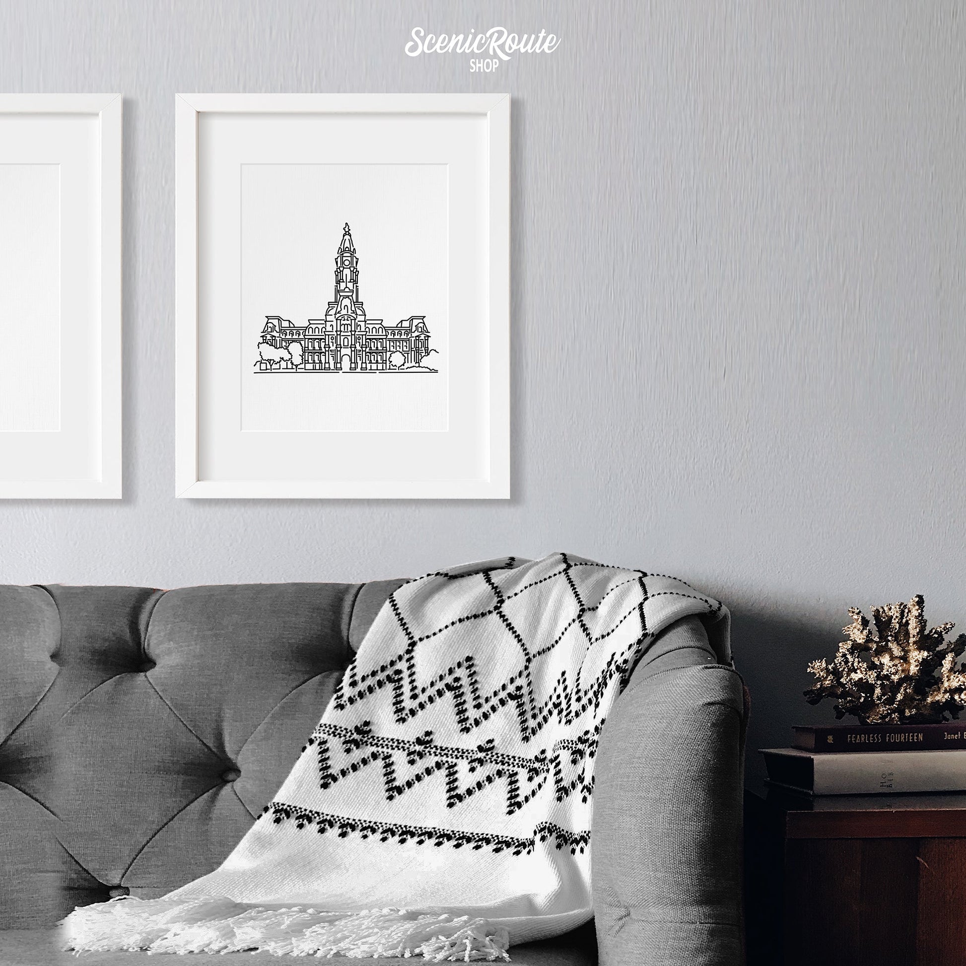 A framed line art drawing of Philadelphia City Hall above a sofa with a blanket