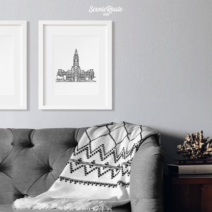 A framed line art drawing of Philadelphia City Hall above a sofa with a blanket