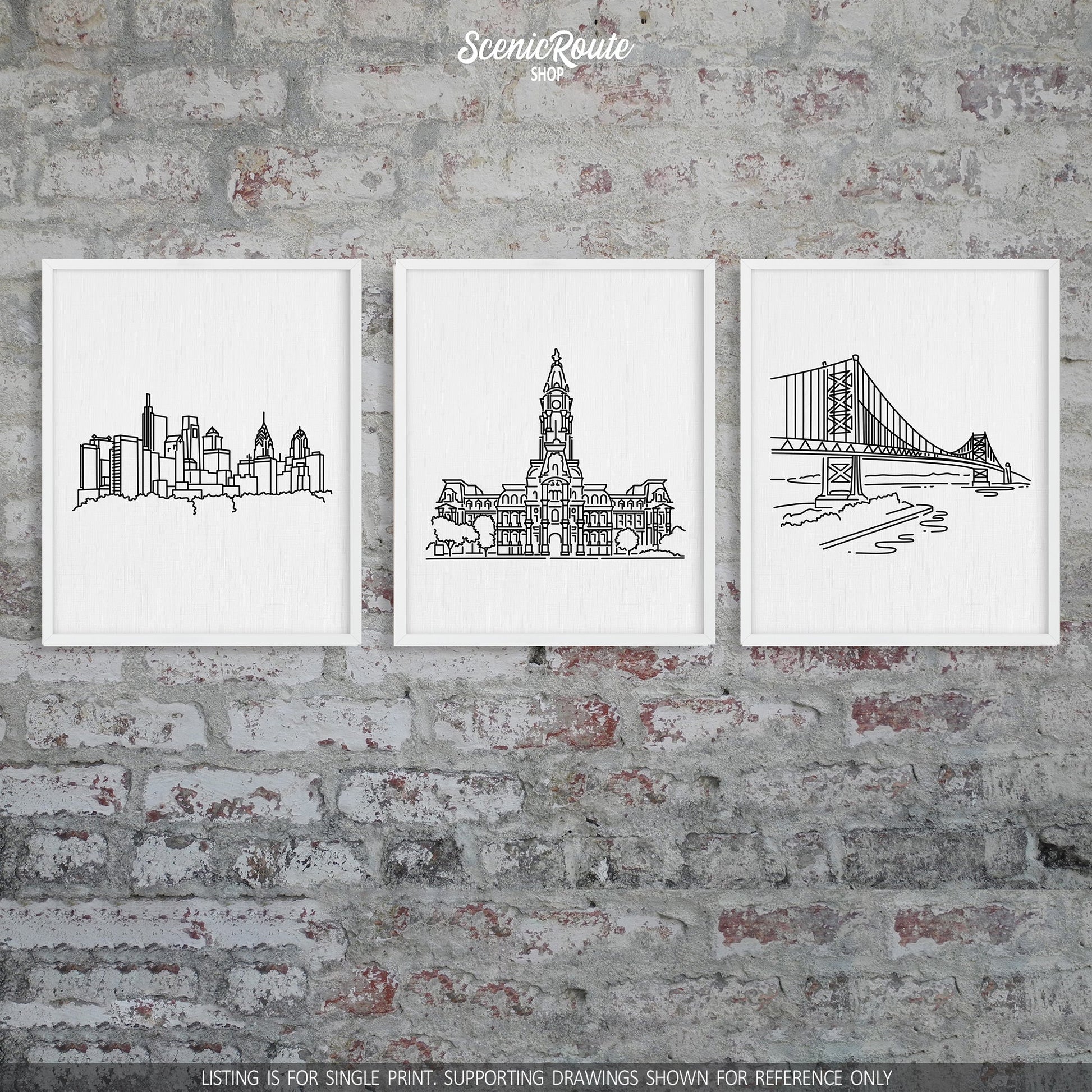 A group of three framed drawings on a brick wall. The line art drawings include the Philadelphia Skyline, Philadelphia City Hall, and Ben Franklin Bridge