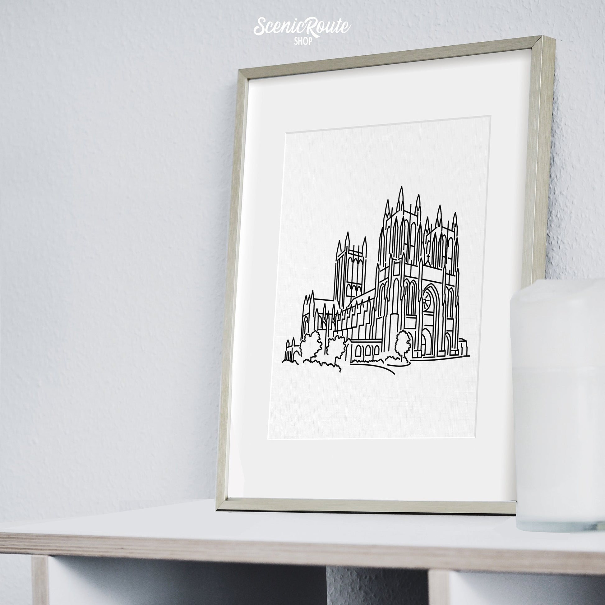 A framed line art drawing of the National Cathedral on a bookcase