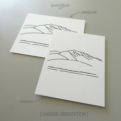 Two line art drawings of Humphreys Peak on white linen paper with a gray background.  The pieces are shown in portrait and landscape orientation for the available art print options.