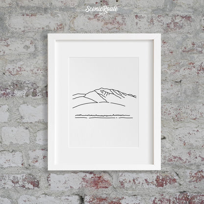 A framed line art drawing of Humphreys Peak on a brick wall