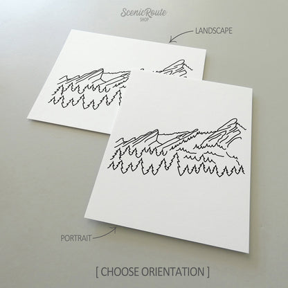 Two line art drawings of The Flatiron Mountains on white linen paper with a gray background.  The pieces are shown in portrait and landscape orientation for the available art print options.
