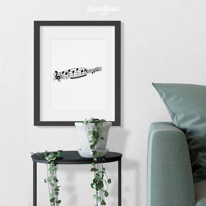 A framed line art drawing of Music Notes above a small table with a plant