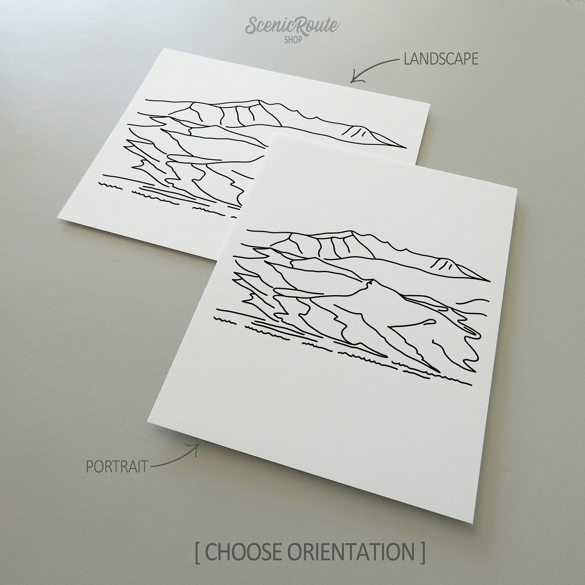Two line art drawings of Great Sand Dunes National Park on white linen paper with a gray background.  The pieces are shown in portrait and landscape orientation for the available art print options.