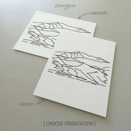 Two line art drawings of Great Sand Dunes National Park on white linen paper with a gray background.  The pieces are shown in portrait and landscape orientation for the available art print options.