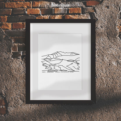 A framed line art drawing of Great Sand Dunes National Park on a rough brick wall