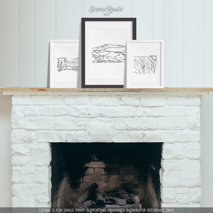 A group of three framed drawings on a fireplace mantle. The line art drawings include Rocky Mountain National Park, Great Sand Dunes National Park, and Black Canyon of the Gunnison National Park